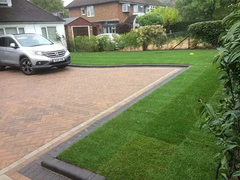 Block paved driveway edged with a strip of freshly laid turf