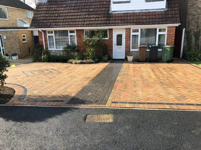 Brindle block paved driveway with a charcoal band and tarmac apron outside a semi-detached house