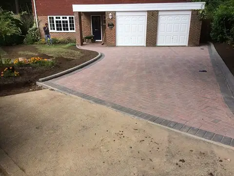 Pink-toned block paved driveway leading to a double garage