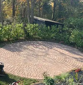Circular clay paver patio set into planted borders