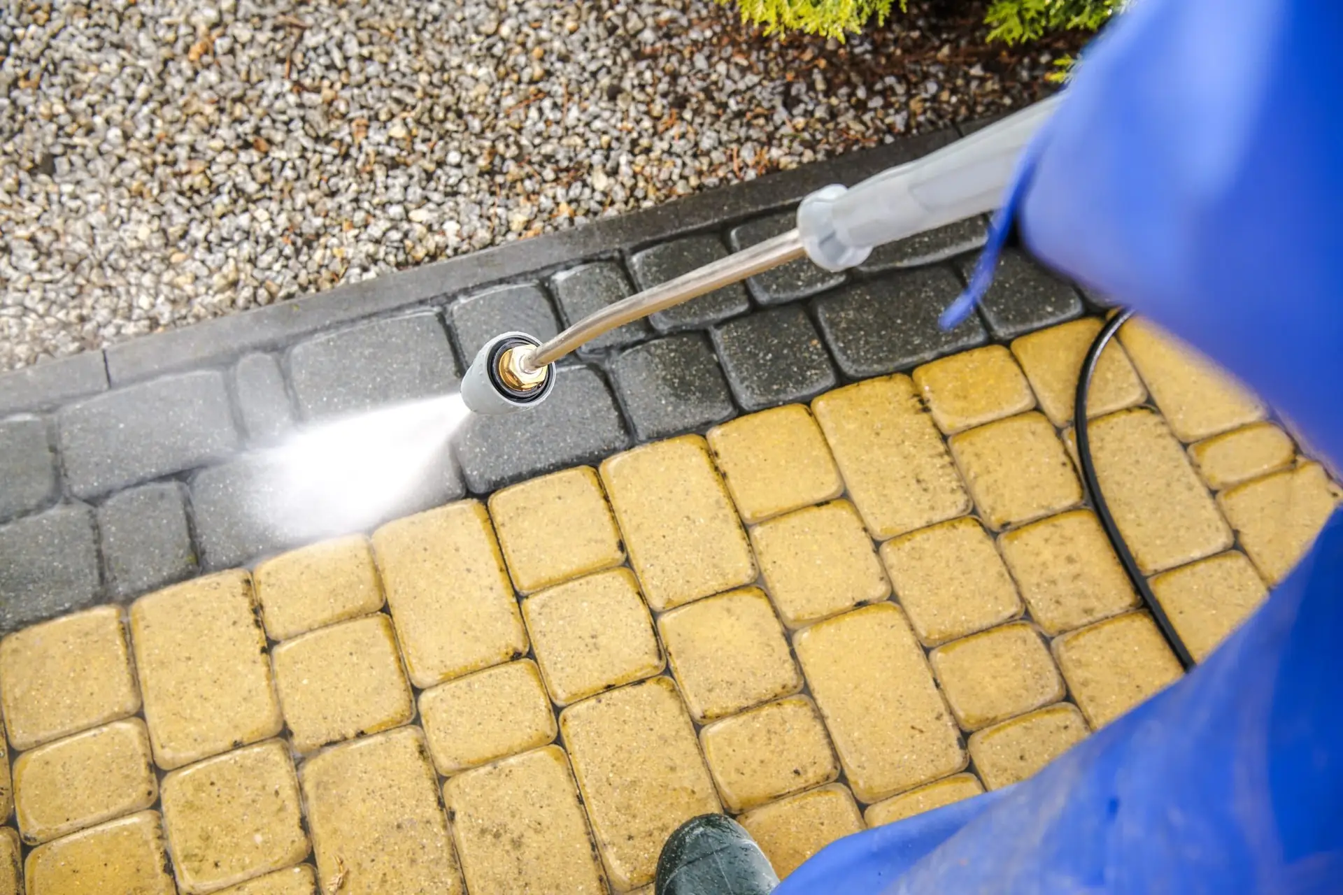 Pressure washer lifting grime from yellow block paving