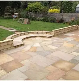 Curved sandstone patio with a raised brick retaining wall behind