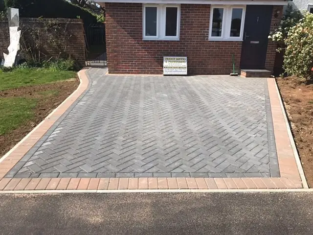 Grey herringbone block paved driveway with a buff border outside a semi-detached house