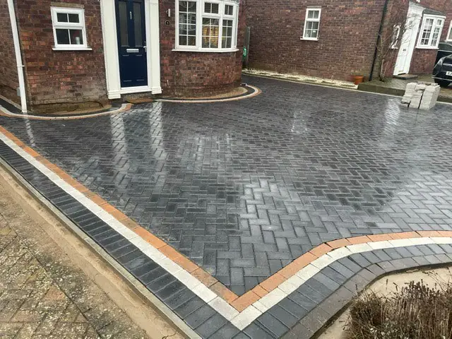 Grey herringbone block paved driveway with a buff and charcoal border, freshly laid