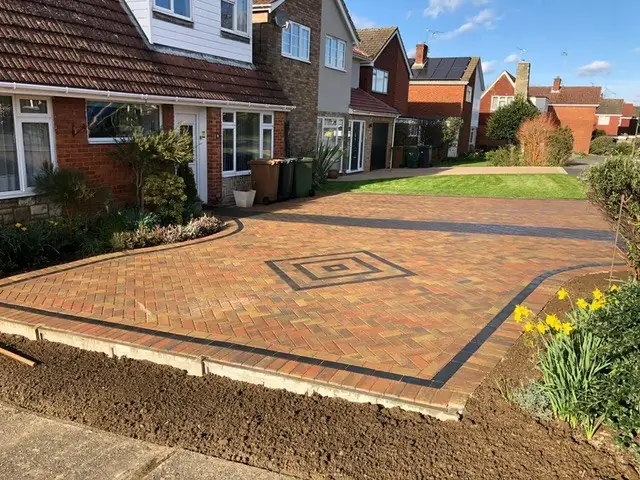 Brindle herringbone driveway with a grey diamond feature and charcoal border across a front garden