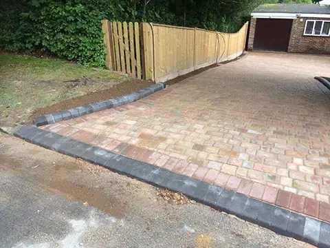 Charcoal kerbs and a red border set along a new tumbled block driveway