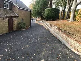 Long tarmac driveway running beside a brick cottage