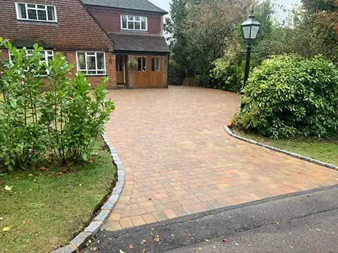 Finished tumbled block driveway after replacement, beside a lamp post and planting