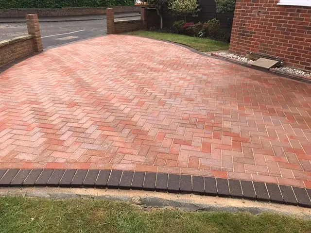 Red clay herringbone driveway finished with a charcoal border and a lawn edge