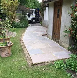 Sandstone path laid along the side of a house beside planting