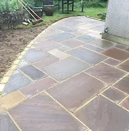 Sandstone patio wrapping around the side of a house
