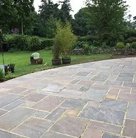 Large sandstone patio opening onto a lawned garden