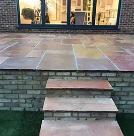 Sandstone steps with brick risers leading down from a patio