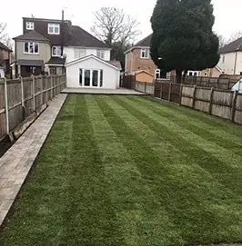 Newly turfed striped lawn running down a fenced back garden