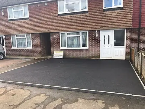 New tarmac driveway with grey block edging in front of a semi-detached house
