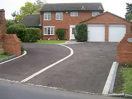 Curving tarmac drive with a white kerb line leading to a double garage